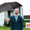 Man holding a black classic Curved Wood Handle Folding Umbrella