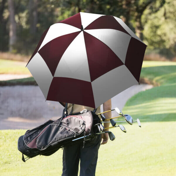 Golfer holding clubs and The Checkerboard umbrella