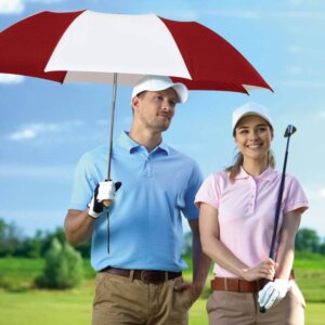 Female and male golfers on a golf course, with the man holding an umbrella. 